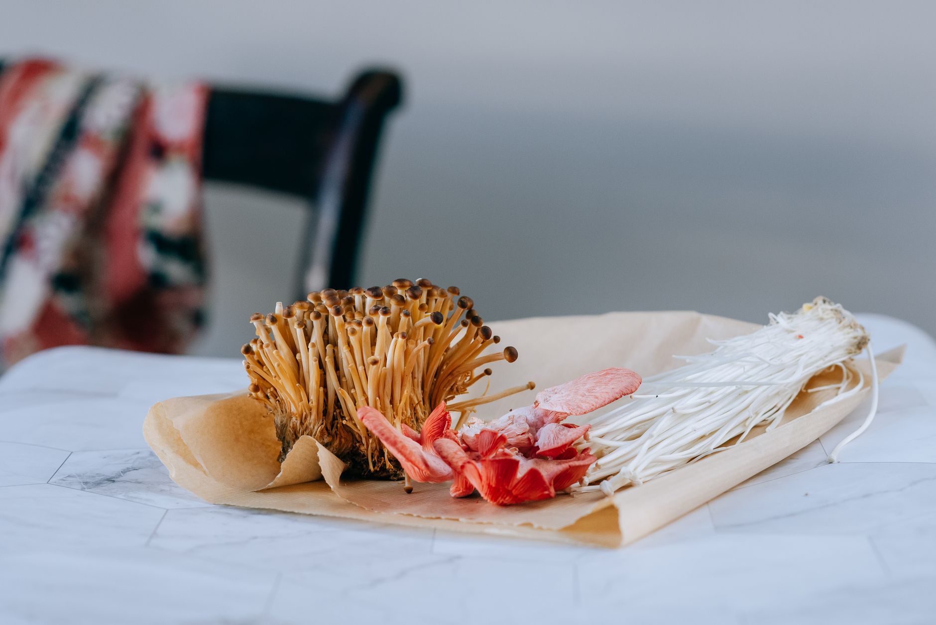 Little brown nameko mushrooms composed with pink oyster and enoki on paper package on blurred background